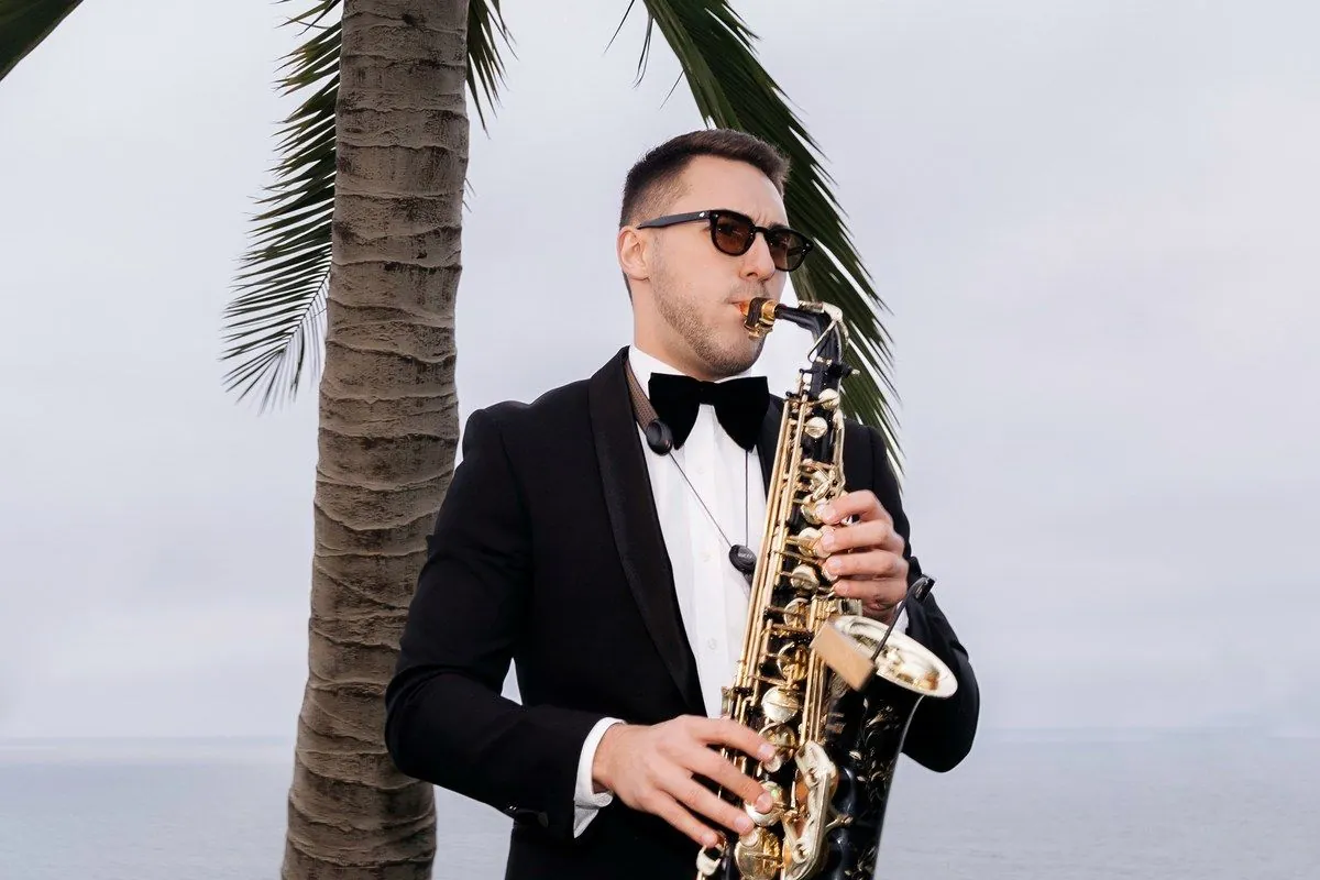 Saxophonist in a tuxedo playing at a beachfront ceremony